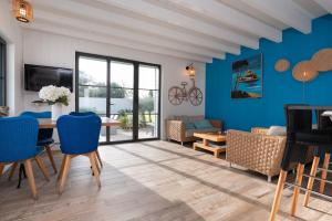ein Wohnzimmer mit blauen Wänden sowie einem Tisch und Stühlen in der Unterkunft La Maison bleue Domainedecolomban in Carnac