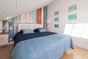 ein Schlafzimmer mit einem Bett mit blauen Laken und einem Fenster in der Unterkunft La Maison bleue Domainedecolomban in Carnac