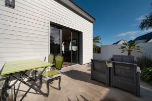 eine Terrasse mit einem Tisch und Stühlen neben einem Gebäude in der Unterkunft La Maison bleue Domainedecolomban in Carnac