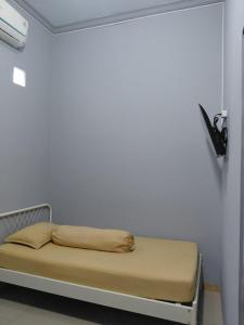 a bed in a room with a white wall at IB Homestay Syariah by Ecommerceloka in Tegal +23 photos
