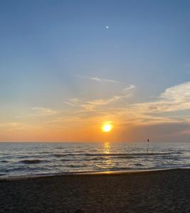 a sunset on a beach with the ocean at Felci 19, apartment 6 beds in Marina di Bibbona just 300 mt from the sea in Marina di Bibbona