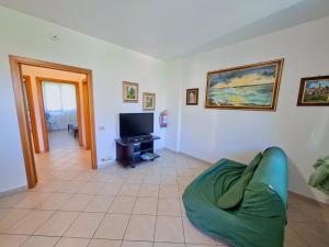 a living room with a green couch and a television at Felci 19, apartment 6 beds in Marina di Bibbona just 300 mt from the sea in Marina di Bibbona