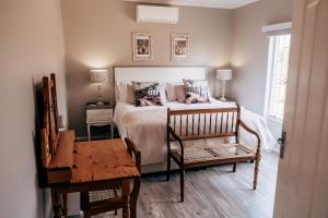 Un dormitorio con una cama con una mesa y una silla. en Shama Guest Farm - A True Klein Karoo Farm Escape, en Oudtshoorn