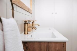 baño con lavabo blanco y grifo de oro en Shama Guest Farm - A True Klein Karoo Farm Escape, en Oudtshoorn 57 fotos más