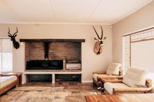 Una sala de estar con chimenea y astas en la pared. en Shama Guest Farm - A True Klein Karoo Farm Escape, en Oudtshoorn