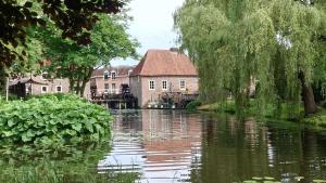 a river with a house in the background next to a building at Oude haven Borculo in Borkulo