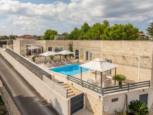 a house with a swimming pool with umbrellas at Unique luxury Villa Feriatum Lissa in Ždrelac