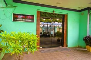 a green building with a door with a sign on it at Hotel Ambika in Jāmb +4 photos