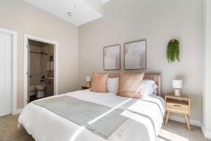 a white bedroom with a large bed and a bathroom at Spacious 2BR CozySuites OTR Downtown #12 in Cincinnati