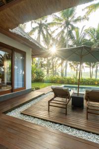 a wooden deck with two chairs and an umbrella at The Lanaya Villa in Ubud