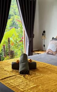a bedroom with a bed with two towels and a window at Little Munduk, full private villa in Munduk