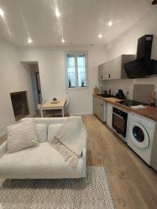 a living room with a white couch and a kitchen at Duplex centre historique - Château et Loire - tout confort élégant et calme in Saumur