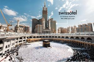 a large crowd of people in a stadium with a clock tower at Swissotel Al Maqam Makkah in Makkah