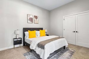 a white bedroom with a large bed with yellow pillows at Spacious 2BR CozySuites OTR Downtown #11 in Cincinnati