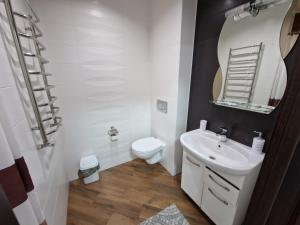a bathroom with a sink and a toilet and a mirror at Luxury Apart in Ivano-Frankivsʼk