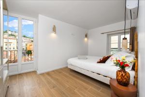 a white bedroom with a bed and a vase with flowers at FELIX FAURE - Somptueux 3 pièces - Carré d'Or Menton - PARKING in Menton