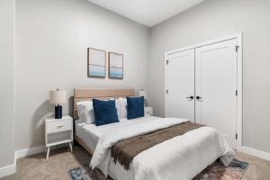 una camera bianca con un grande letto con cuscini blu di CozySuites Modern 3BR OTR District #17 a Cincinnati