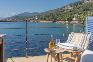a table and chairs on a balcony with a view of the water at Maison de pêcheur dans le Cap Corse in Erbalunga