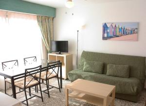 sala de estar con sofá verde y mesa en Apartamentos Nere, en Benidorm