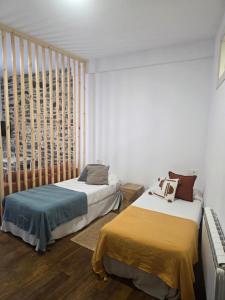 two beds in a room with white walls and wood floors at Estudio Casco Histórico Betanzos in Betanzos