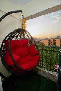 un sillón colgante con almohadas rojas en el balcón en Happy Crest Airbnbs, en Nairobi