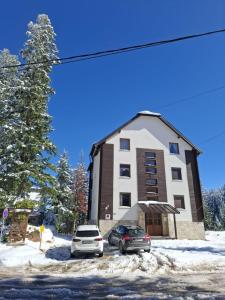 un gran edificio con dos coches estacionados frente a él en Apartment Oganj, en Jahorina