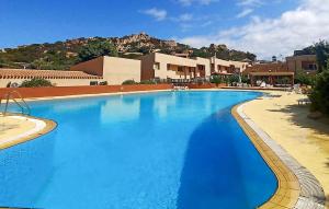 a large blue swimming pool with a mountain in the background at Beautiful Apartment In Costa Paradiso in Trinità dʼAgultu