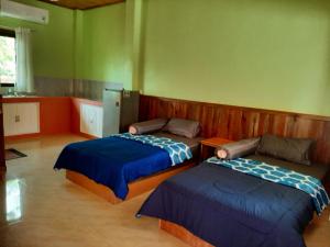 two beds in a room with green walls at Baan Berm Family Inn 