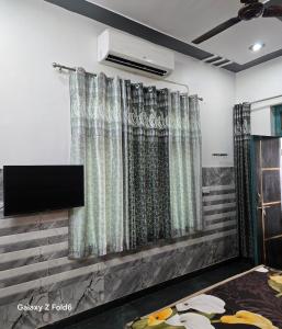 a room with curtains and a flat screen tv at Shera farm in Khatauli