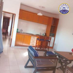 a kitchen with wooden cabinets and a table and chairs at Residhome ACACIA in Moanda