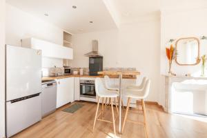 a kitchen with white appliances and a table with stools at Spacious & bright apartment - Top location in Toulon +3 photos