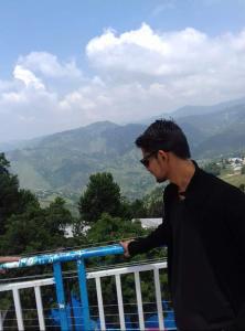 a man leaning on a rail looking at a view at Nabeel Hotel in Dargai