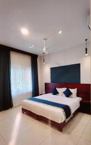 a bedroom with a large bed with blue pillows at Citadel Boutique Hotel Thekkady in Jāmb