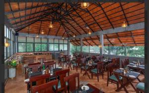 a restaurant with wooden tables and chairs and windows at Citadel Boutique Hotel Thekkady in Jāmb