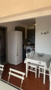 a kitchen with a white table and chairs and a refrigerator at Studio-Soleil Levant 1-Grande plage-Le Barcarès in Le Barcarès