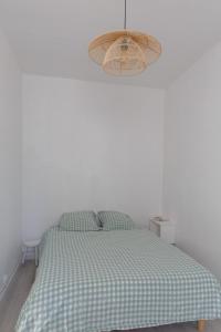 a bed in a white room with a checkered blanket at appartement entre plages et centre historique in Concarneau
