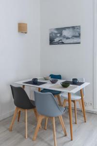 a white table with chairs and a white wall at appartement entre plages et centre historique in Concarneau