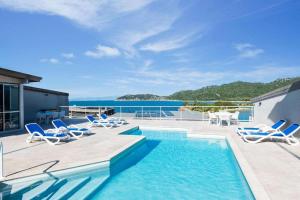 a swimming pool with lounge chairs and the ocean at Luxury Oceanview Escape in Nelly Bay