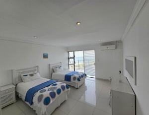 two beds in a room with white walls at LaPeroge Home in Ballito