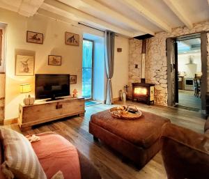 a living room with a couch and a television and a fireplace at Coume a Case - Maison de charme 4 étoiles - piscine et spa - vallée d'Ossau in Lys