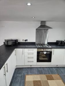 Una cocina con gabinetes blancos y un horno de estufa. en The coach house, en Nottingham 4 fotos más