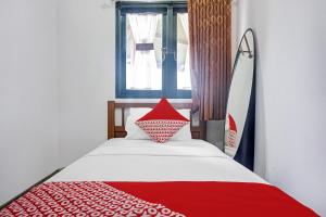 a bedroom with a red and white bed with a window at Hotel O 90596 Hotel Griya Astoeti in Bogor