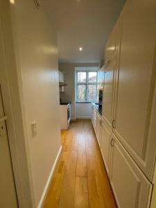 コペンハーゲンにあるComfy Valby Retreatの白いキャビネットと木製の床を備えたキッチン