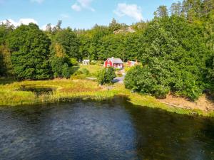 a river with a red house next to a forest at Knaggelid Guest Houses in Svängsta