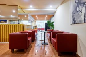 a waiting room with red chairs and a table at Hotel Strudlhof Vienna in Vienna