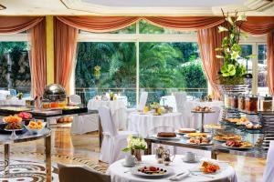 Un restaurante con mesas y sillas blancas y un gran ventanal. en Parco dei Principi Grand Hotel & SPA, en Roma