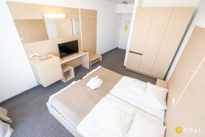 a room with a bed and a desk and a television at Hotel Opal in Jupiter