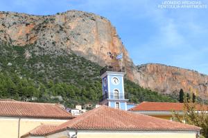 un edificio con una torre dell'orologio di fronte a una montagna di Rentoulia Apartments a Poúlithra Altre 38 foto