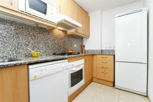 een keuken met witte apparaten en houten kasten bij Apartamento ROURA in La Pineda