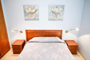 een slaapkamer met een bed met twee tafels en bloemen bij Apartamento ROURA in La Pineda +15 foto's
